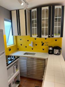 Una cocina con un fregadero y una pared amarilla. en Praia Grande Aviação Apto Disney, en Praia Grande