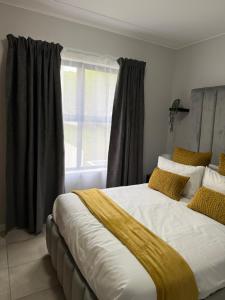 een slaapkamer met een groot bed met gele kussens en een raam bij Elevare suites in Nelspruit