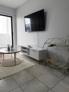 een woonkamer met een tafel en een tv aan de muur bij Elevare suites in Nelspruit