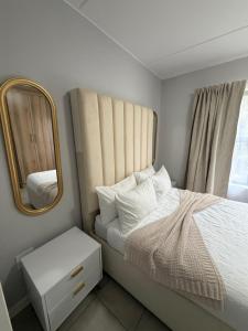 een kleine slaapkamer met een bed en een spiegel bij Elevare suites in Nelspruit