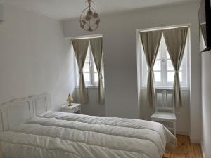 een slaapkamer met een wit bed en 2 ramen bij Melro-d' água in Manteigas