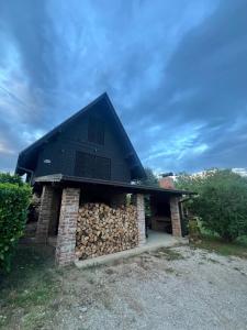 a house with a black roof and a pile of wood at Podroom LauMarYvo in Dugo Selo