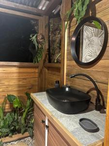a bathroom with a black sink and a mirror at Lodges atypiques, filet suspendu ou lit mobile pour expérience unique sous les etoiles in Petit-Bourg