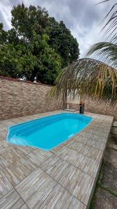 a small blue swimming pool next to a brick wall at Paraíso Tropical em Porto Seguro in Porto Seguro