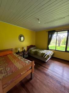 1 dormitorio con 2 camas en una habitación con paredes amarillas en Casa en Panguipulli, en El Cerrillo