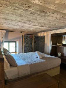 a bedroom with a large bed with a wooden ceiling at Victoria Tiny Stone House in Ponta do Pargo