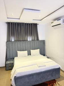 MamaMsquare Comfort Hotel的一间卧室配有一张大床和灰色床头板