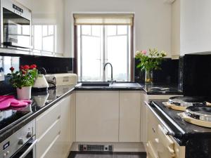 a kitchen with white cabinets and a sink at Beacon Cottage in Ivybridge
