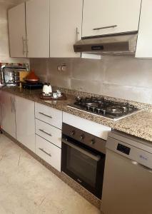 a kitchen with white cabinets and a stove top oven at Rabat Explorer Apartment in Rabat
