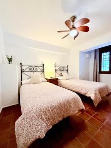 zwei Betten in einem Schlafzimmer mit Deckenventilator in der Unterkunft Casa Rural Orilla del Hueznar in Cazalla de la Sierra