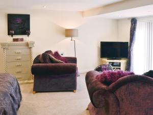 a living room with two chairs and a tv at Stable Cottage in Penrhyn Bay