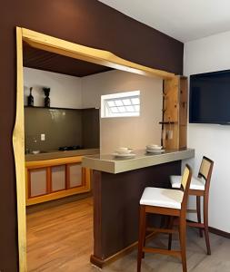 une cuisine avec un comptoir, une table et des chaises dans l'établissement Flat Ruanda para casal em meio à natureza!, à Nova Friburgo