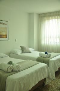 a room with three beds with towels on them at live Medellín desde un Apartamento Céntrico y Cómodo in Medellín