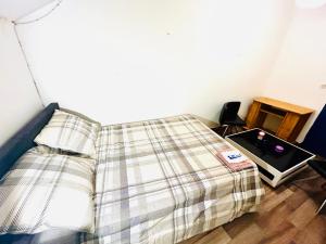 a bed with a plaid blanket next to a table at Christalsuite in Frameries