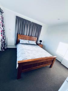 a bedroom with a large bed with a wooden headboard at Holiday Home In Red Hill Papakura Auckland in Buckland