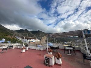 a patio with tables and chairs on a roof at Nouara Appart'Hotel in Chefchaouen