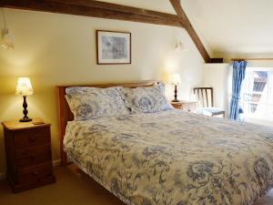 a bedroom with a bed and two lamps and a window at Swallows Cottage in Tipton Saint John +3 photos