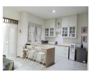 a kitchen with white cabinets and a kitchen island with stools at Vila Kuntum Bogor- 3BR Cozy House dekat Kuntum Farmfield in Ciawi