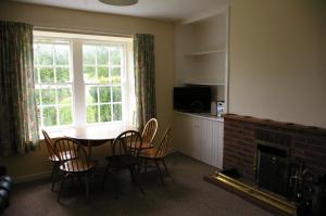 a living room with a table and chairs and a fireplace at The Cottage in Etal