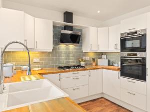 une cuisine avec des armoires blanches et un évier dans l'établissement Carew Cottage, à Manorbier