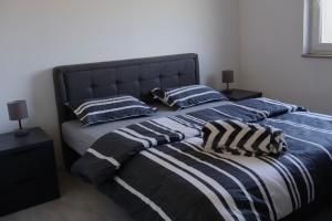 two beds with striped blankets and pillows in a bedroom at Apartmani Ana in Čapljina