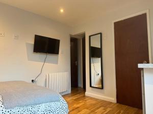 a bedroom with a bed and a flat screen tv on the wall at Studio with en suite, compact and comfortable for 1-2 people in Luton +10 photos