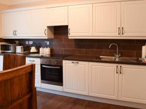 a kitchen with white cabinets and a sink at Craven House in West Burton