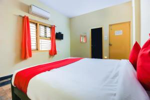a bedroom with a bed with red pillows and a window at Hotel O Sai Residency Near SR Nagar metro station in Hyderabad