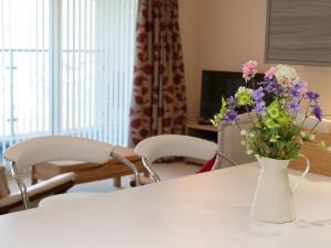 een witte tafel met een vaas met bloemen erop bij Apartment 5 Latitude 51 Westward Ho! in Westward Ho