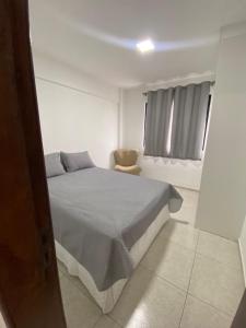a white bedroom with a bed and a chair at Joan Miro Flat - Ponta Negra in Natal +7 photos