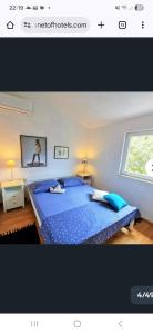a bedroom with a large blue bed with a window at Apartmani Aurelia in Veliki Drvenik