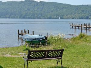 eine Bank neben einem Boot auf einem See in der Unterkunft 3 Townhead Cottages in Grasmere