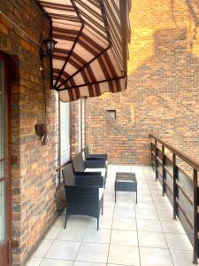 a patio with chairs and a table and a brick wall at Entire Apartment in Eldoraigne, Centurion in Eldoraigne +10 photos
