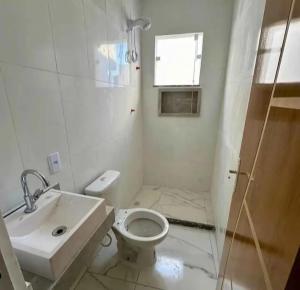 a white bathroom with a toilet and a sink at Quarto de descanso na baixada in Mesquita