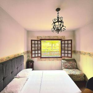 Schlafzimmer mit einem Bett, einem Fenster und einem Kronleuchter in der Unterkunft APART Deluxe Campos do Jordāo com lareira in Campos do Jordão