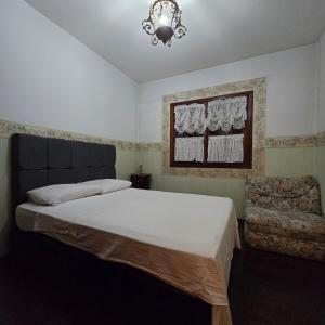 ein Schlafzimmer mit einem Bett, einem Stuhl und einem Kronleuchter in der Unterkunft APART Deluxe Campos do Jordāo com lareira in Campos do Jordão