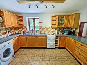 a kitchen with wooden cabinets and a washer and dryer at Fox Cottage - E4510 in Chipping Sodbury