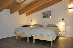 two beds in a white room with wooden ceilings at Giardino di Lei, appartamento giallo in Montegrotto Terme