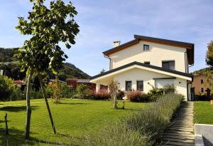 a white house with a grassy yard at Giardino di Lei, appartamento giallo in Montegrotto Terme