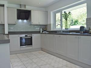 a kitchen with white cabinets and a sink and a window at Manesty in Applethwaite