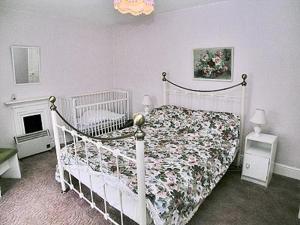 a bedroom with a white bed with a floral bedspread at Tacker Street Cottage in Withycombe