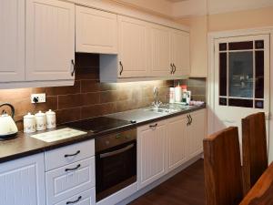 a kitchen with white cabinets and a sink at Craven House in West Burton