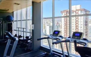 a gym with cardio machines and a large window at FLAT de luxo mobiliado na Savassi in Belo Horizonte