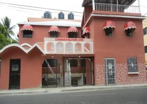 a red building with red accents on a street at Puerto Plata Home in San Felipe de Puerto Plata