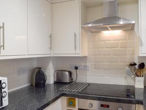 Una cocina con gabinetes blancos y encimera. en 1 Greta Side Court, en Keswick