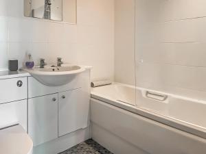 a white bathroom with a sink and a bath tub at 2 Greta Grove House in Keswick +3 photos