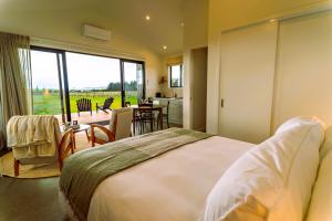 a bedroom with a large white bed and a kitchen at Harvest Rise Vineyard Cottage in Pahautea