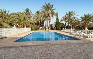 a swimming pool with palm trees and a white fence at Lovely Home In Elda With Private Swimming Pool, Can Be Inside Or Outside in Almafrá