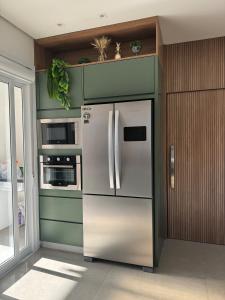 a kitchen with a stainless steel refrigerator and microwave at Sua casa em pdetorres in Passo De Torres