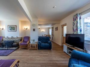 een woonkamer met blauwe stoelen en een flatscreen-tv bij Old Alton Hall Farmhouse in Tattingstone